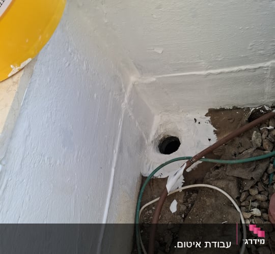 איטום קיר עם חומר לבן ליד צינור וניקוז